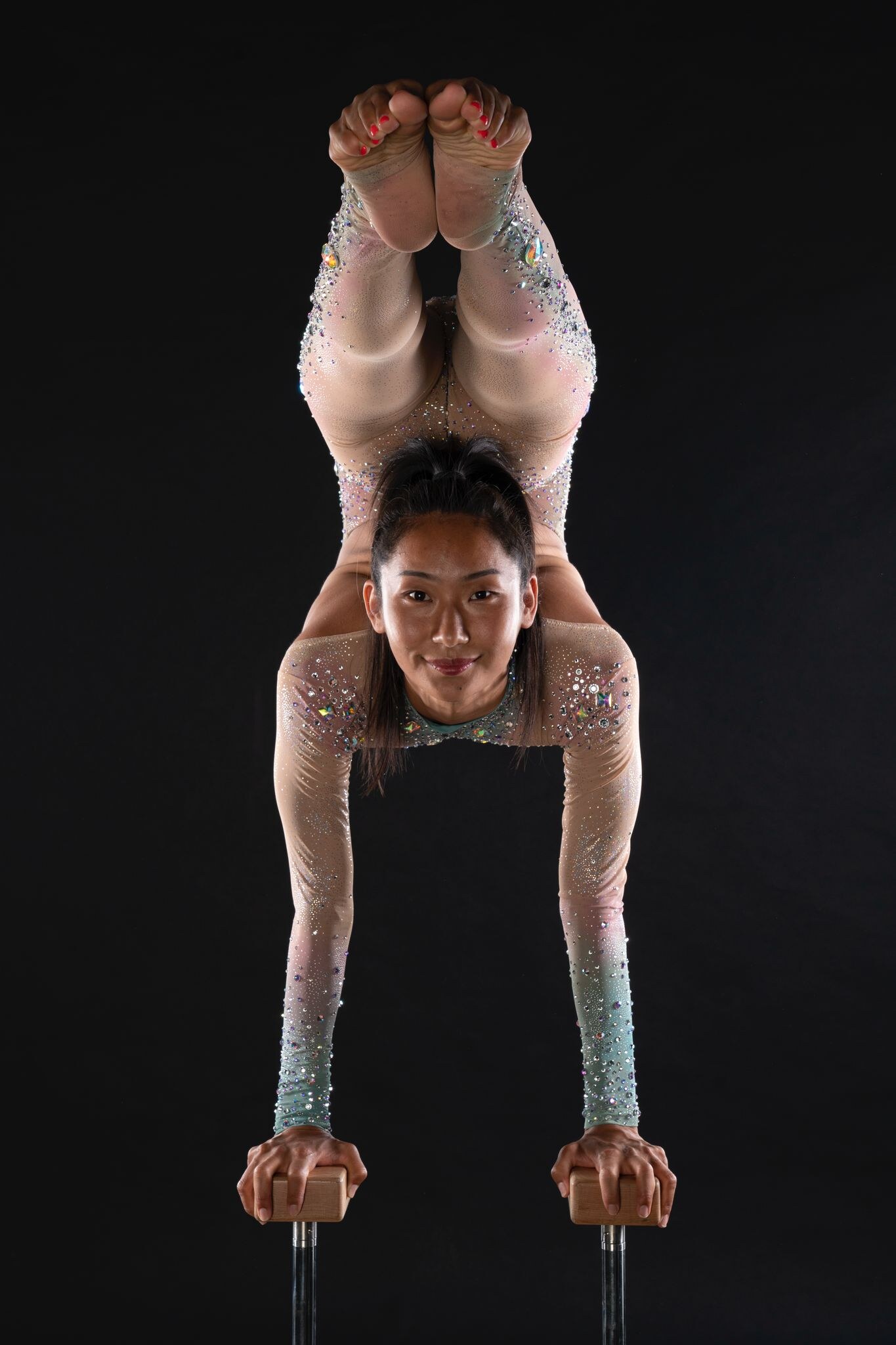 Ulzii balancing in a contortion pose on handstand canes